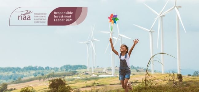 Photo of a young girl chasing a windmill with wind turbine in background