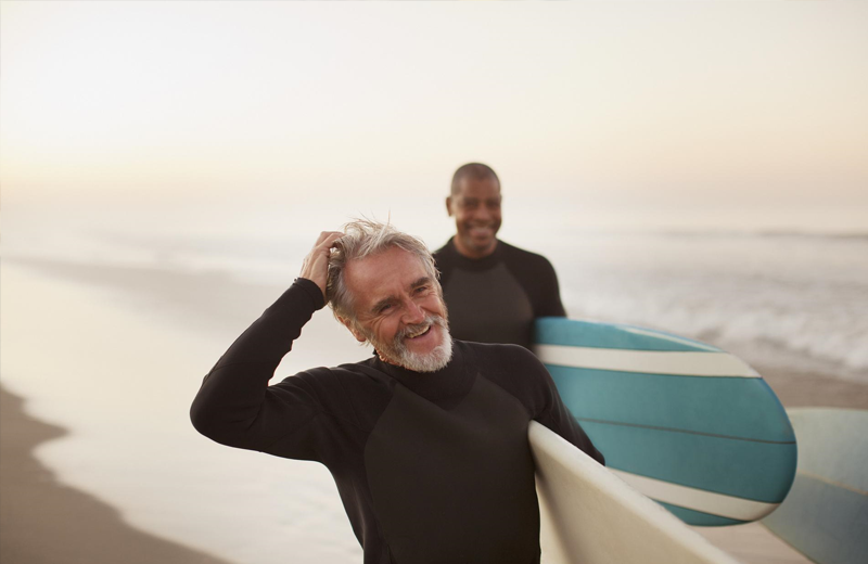 Two males carrying their surfboards.