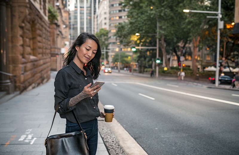 A young woman commuting between work and home, smiling down at her phone.