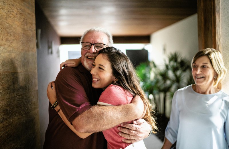 An old man and young adult woman hugging
