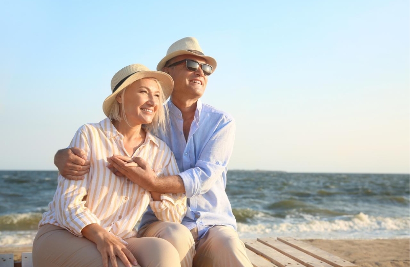 A middle aged couple sitting at a beach and looking out into the distance