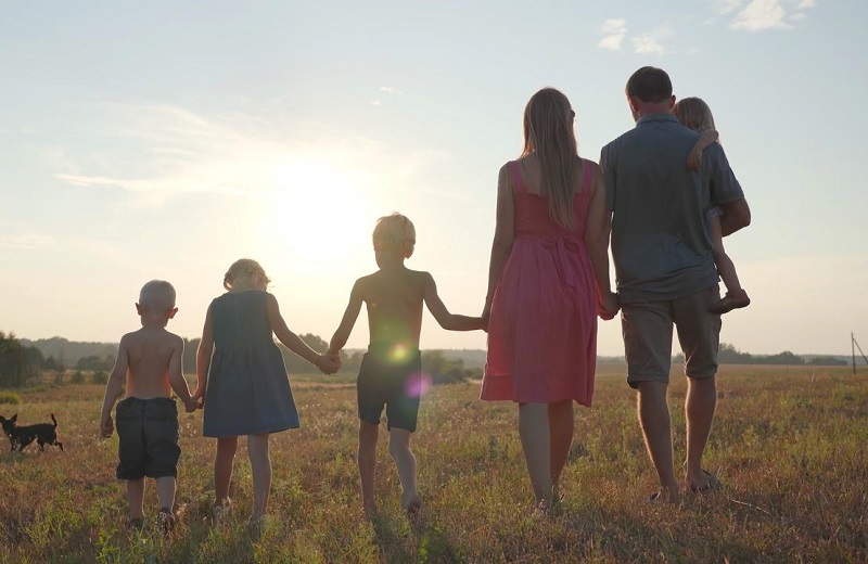 A family of six in a field, facing away