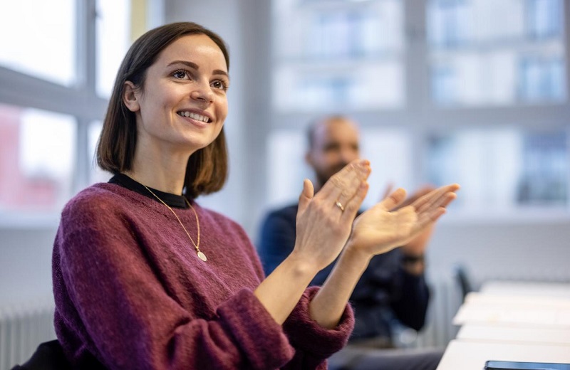 Young woman in office applauding